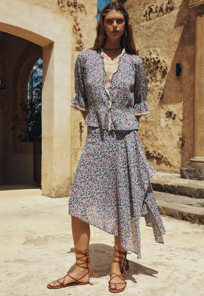 Model wearing Violet Fields floral skirt, front view showing asymmetric waterfall hem and side opening