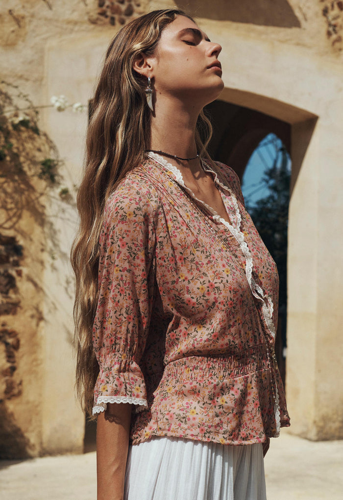 Model side profile showing lace-trim neckline and shirred waist on Pink Posey floral blouse