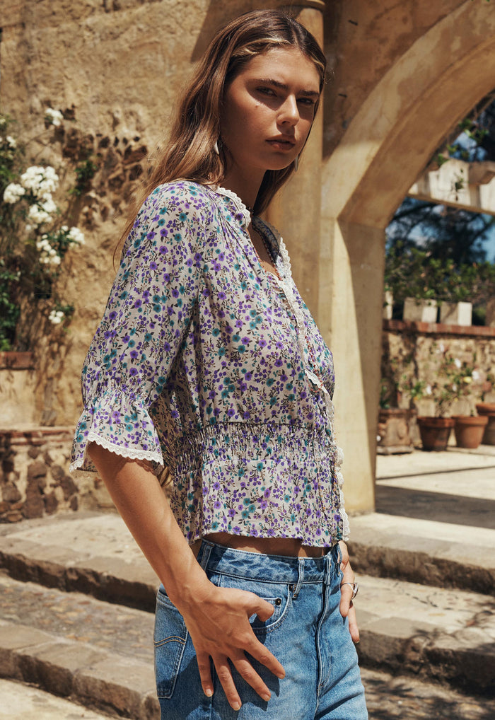 Model side view of Mimi-Rose Blouse, lace-trim neckline, shirred waist, floral print, paired with blue jeans