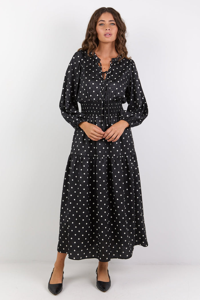Woman wearing a black dress with white patterns on a white background