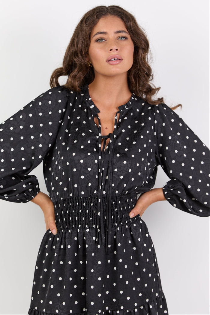 Woman wearing a black polka dot dress against a white background