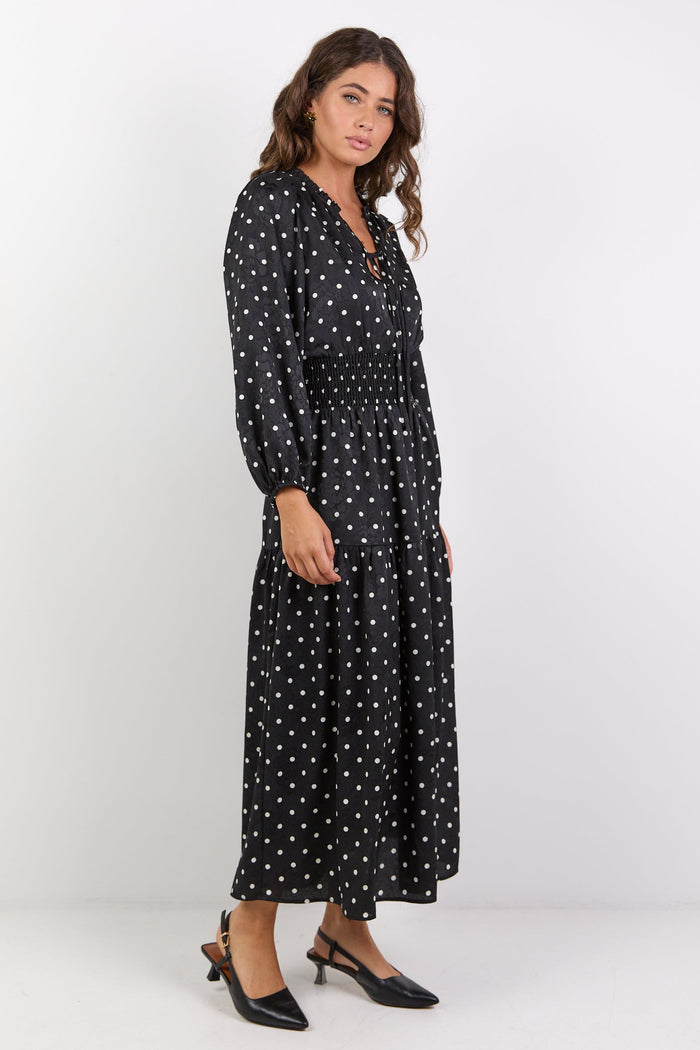 Woman wearing a black dress with white patterns on a white background