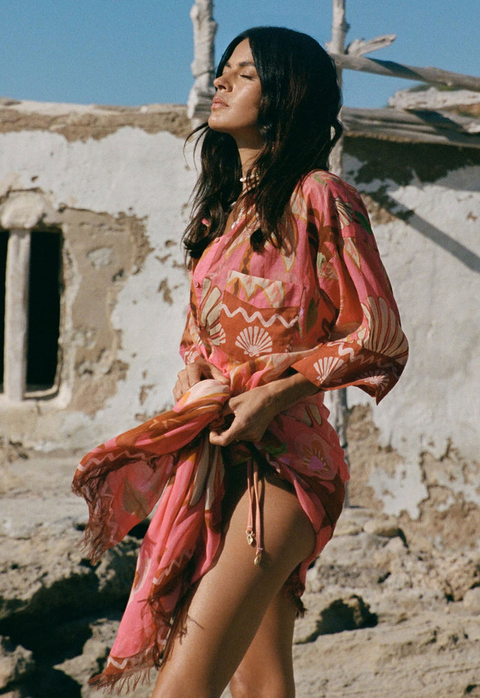 Side view of model wearing coral shell-print Modal scarf tied at waist with frayed edges, outdoors