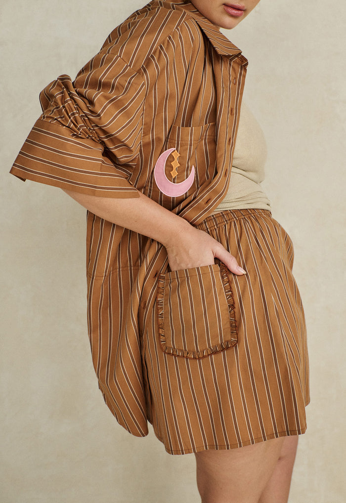 Side view of striped organic cotton mini skirt with frill-trim back pocket and moon appliqué detail