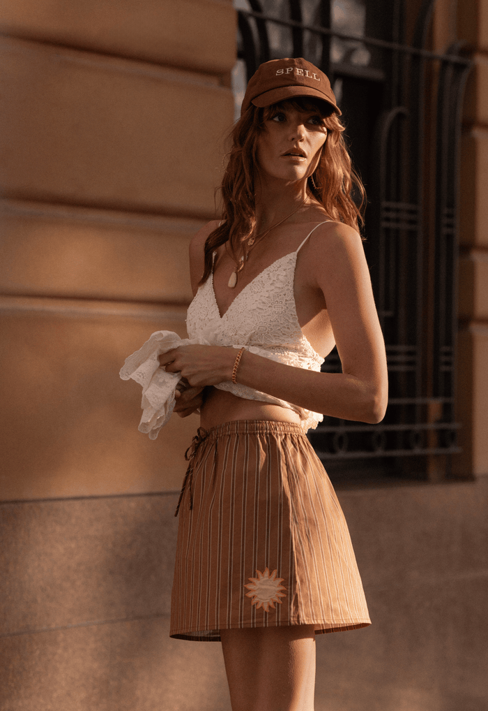 Model wearing Off Duty Mini Skirt side angle, showing waist tie, stripe print and sun applique detail