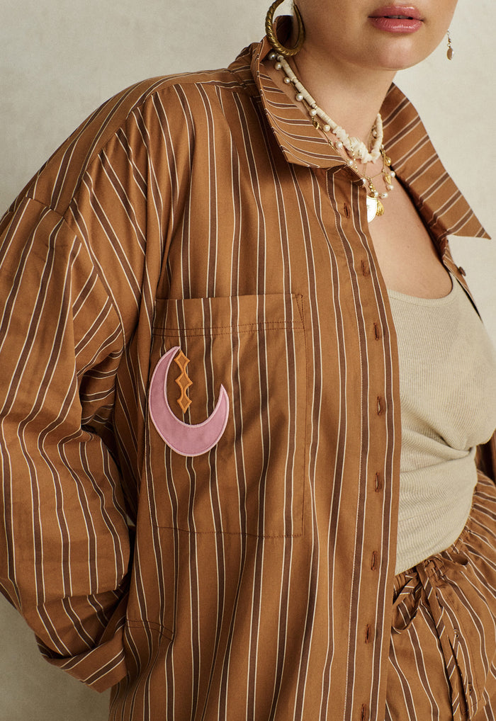 Caramel stripe organic cotton shirt, front view showing chest pocket with pink crescent moon applique detail