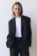 Person wearing a black suit and white shirt against a plain background