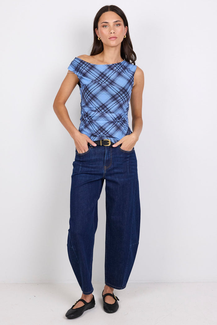 Woman wearing a blue plaid top and dark blue jeans on a white background