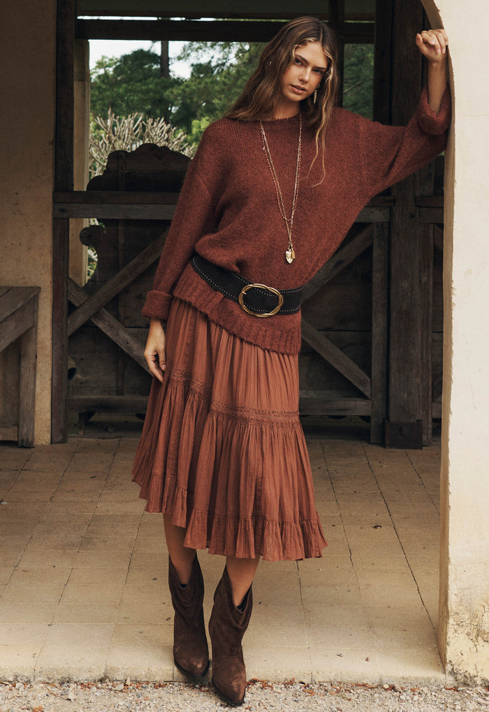 Model wearing Prairie Midi Skirt in Brownie, front view styled with oversized knit and cowboy boots