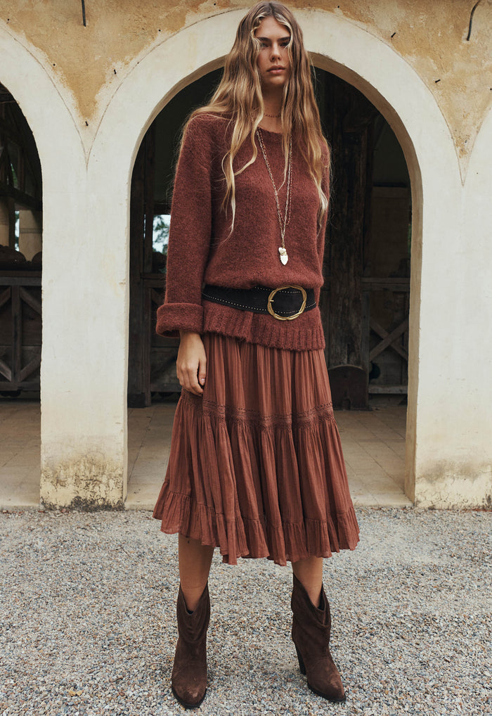 Model wearing Prairie Midi Skirt in Brownie, front view styled with knit sweater and cowboy boots