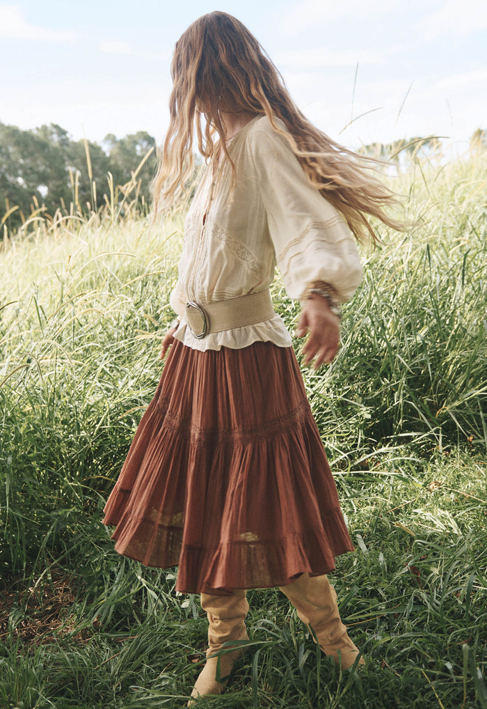 Model wearing Prairie Midi Skirt in Brownie, side view showing tiered organic cotton skirt with embroidered hem frill