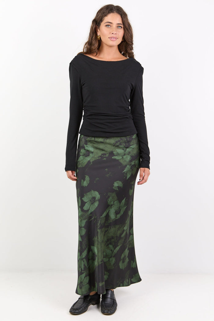 Woman wearing a black long-sleeve top and green camouflage skirt on a white background