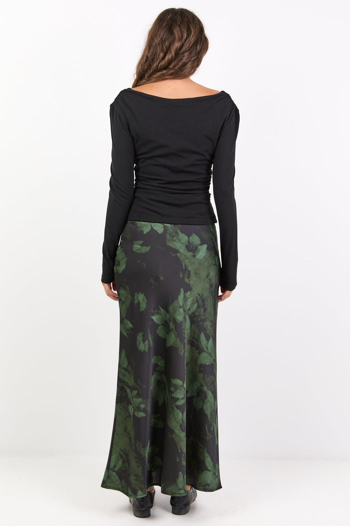 Woman wearing a black long-sleeve top and green camouflage skirt on a white background