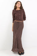 Woman wearing a brown button-up shirt and patterned skirt on a white background