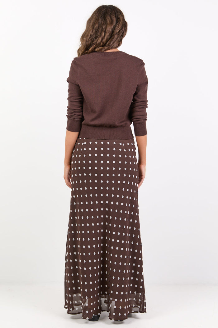 Woman wearing a brown top and patterned skirt on a white background