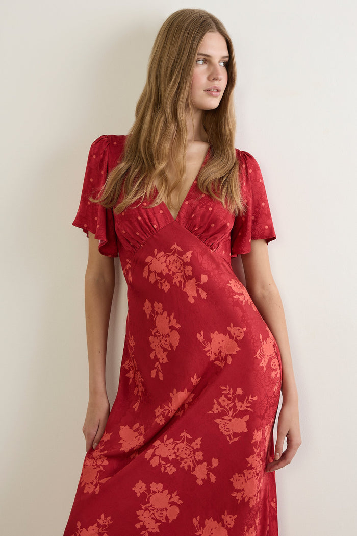 Woman wearing a red floral dress against a plain background