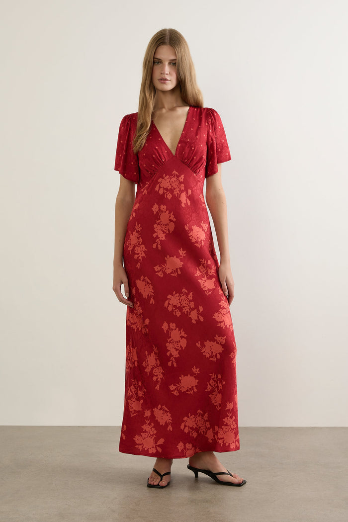 Woman wearing a red floral dress against a plain background