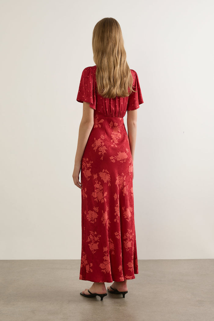 Woman wearing a red floral dress against a white background
