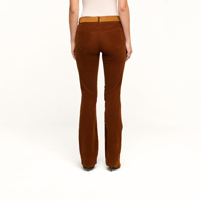 Wearing the Saffia Corduroy Pant, a person stands with their back to the camera against a plain white background, paired with a beige top.