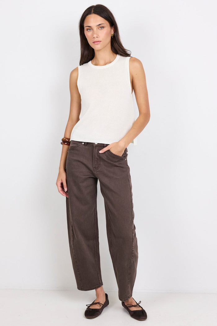 Woman wearing a white knit sleeveless top against a plain background