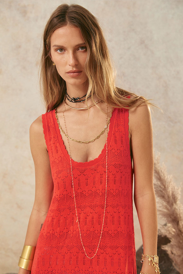 Front detail of chilli red pointelle knit maxi dress with scallop neckline, styled with layered gold necklaces