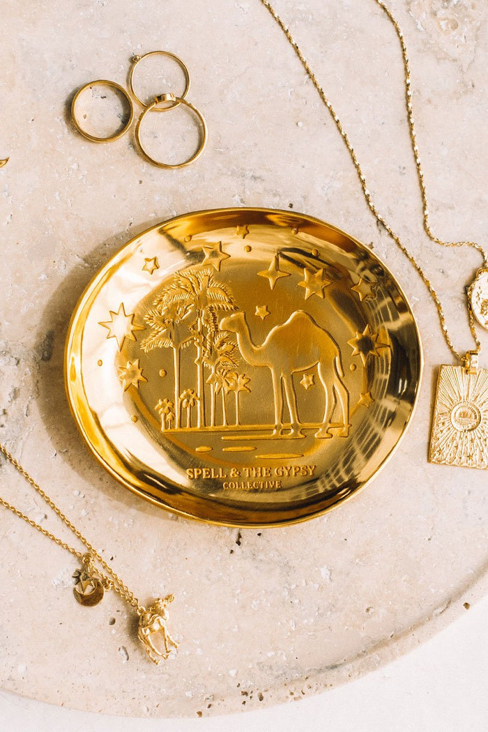 An overhead image of gold jewellery surrounding the gold plated Spell Jewellery Dish with a ‘starry night with camels’ etching.