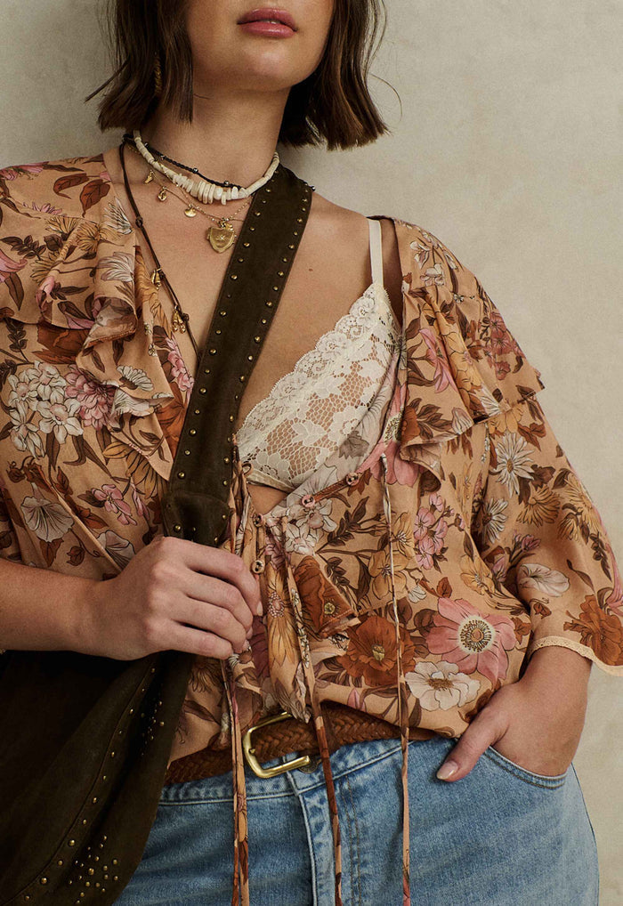 Rose Quartz floral blouse laid flat, front view showing neck ruffle, front ties, and lace-trim shaped hem