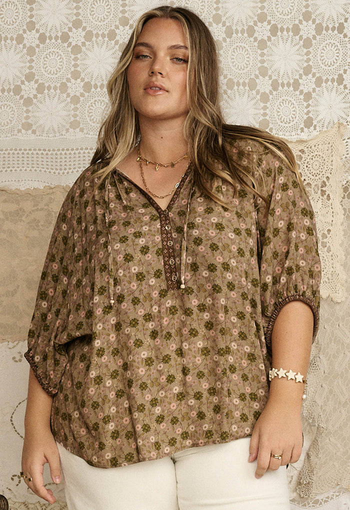 Model wearing Swan Lake blouse in sage, front view showing floral print, neck ties and contrast border sleeve hem detail