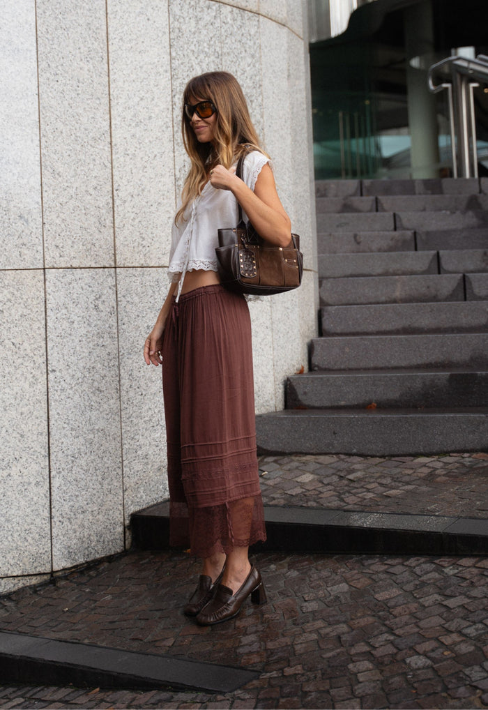 Side view of a model wearing fudge Teodora Lace Pantaloon, showing lace hem, pintucks, and elastic waist with street styling