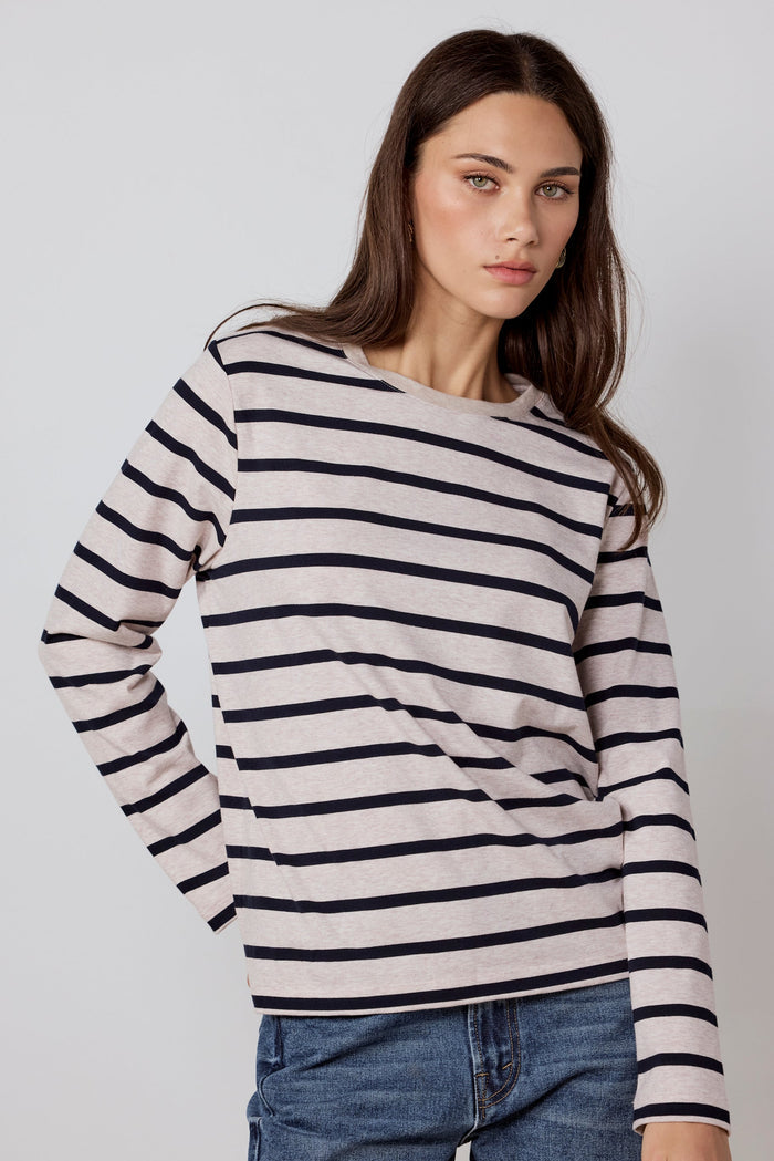 Woman wearing a black and white striped sweater with blue jeans on a plain background