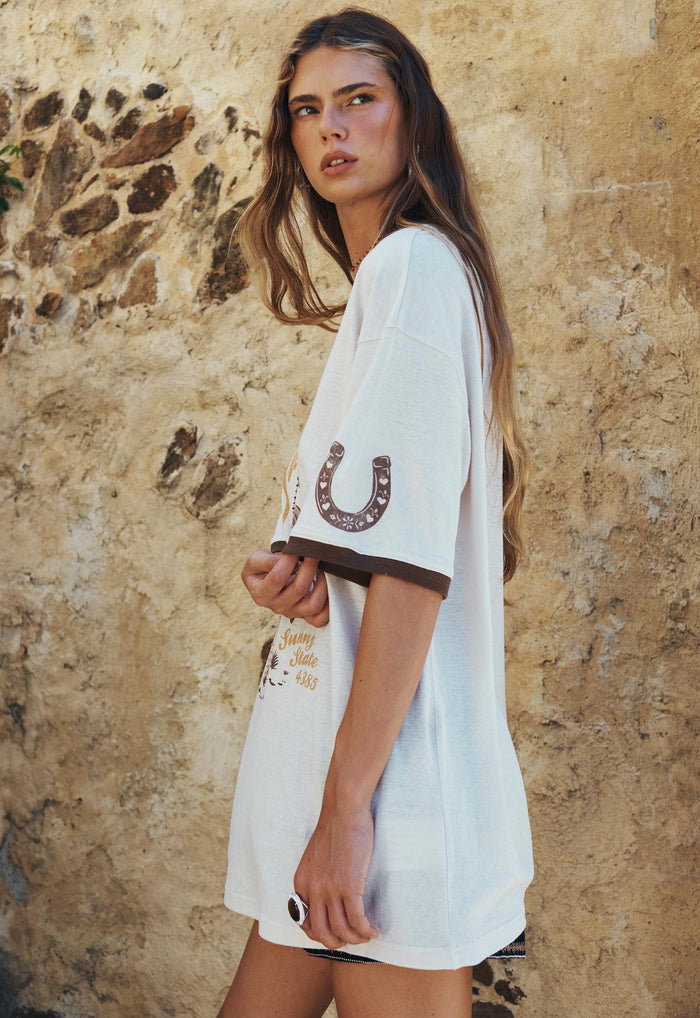 Side view of a model in Texas Sweetheart oversized tee, showing horseshoe print and contrast brown sleeve rib