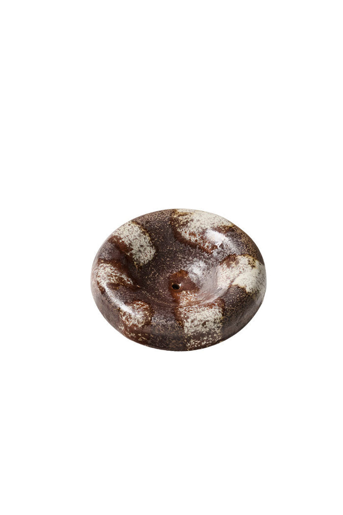 Top-down view of round ceramic incense holder with chocolate and cream stripe glaze finish