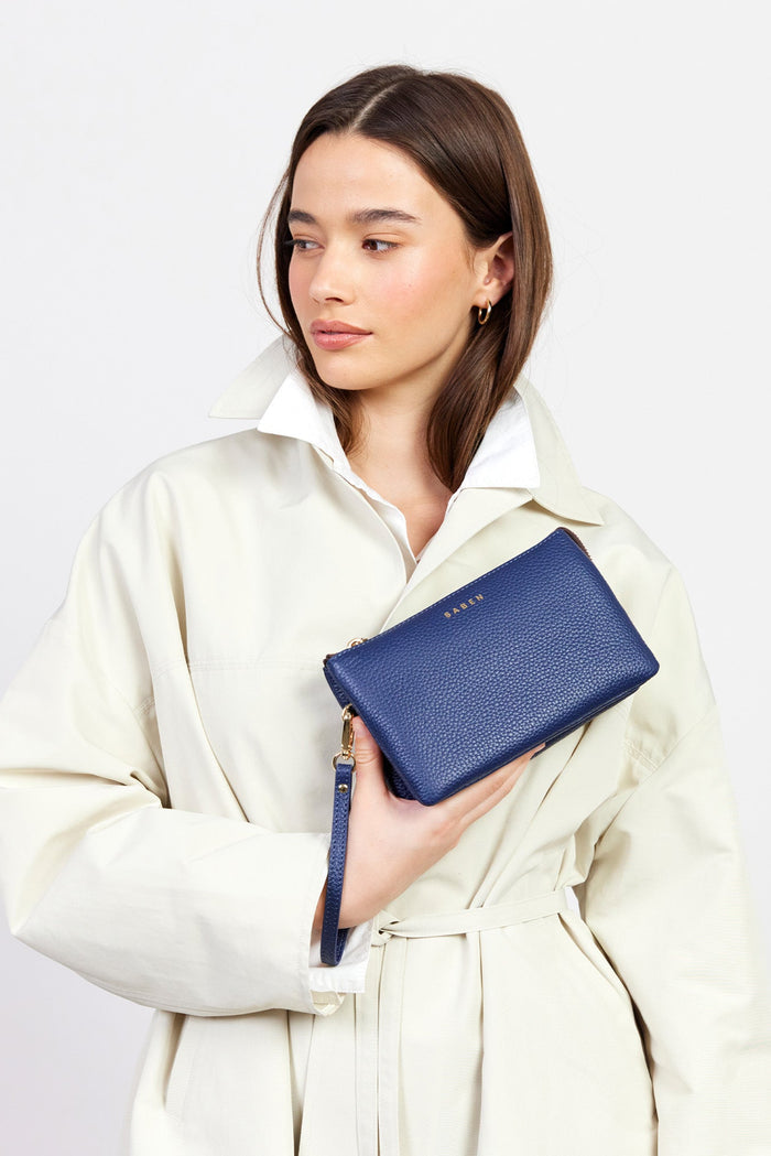 Woman holding a blue wallet against a light background