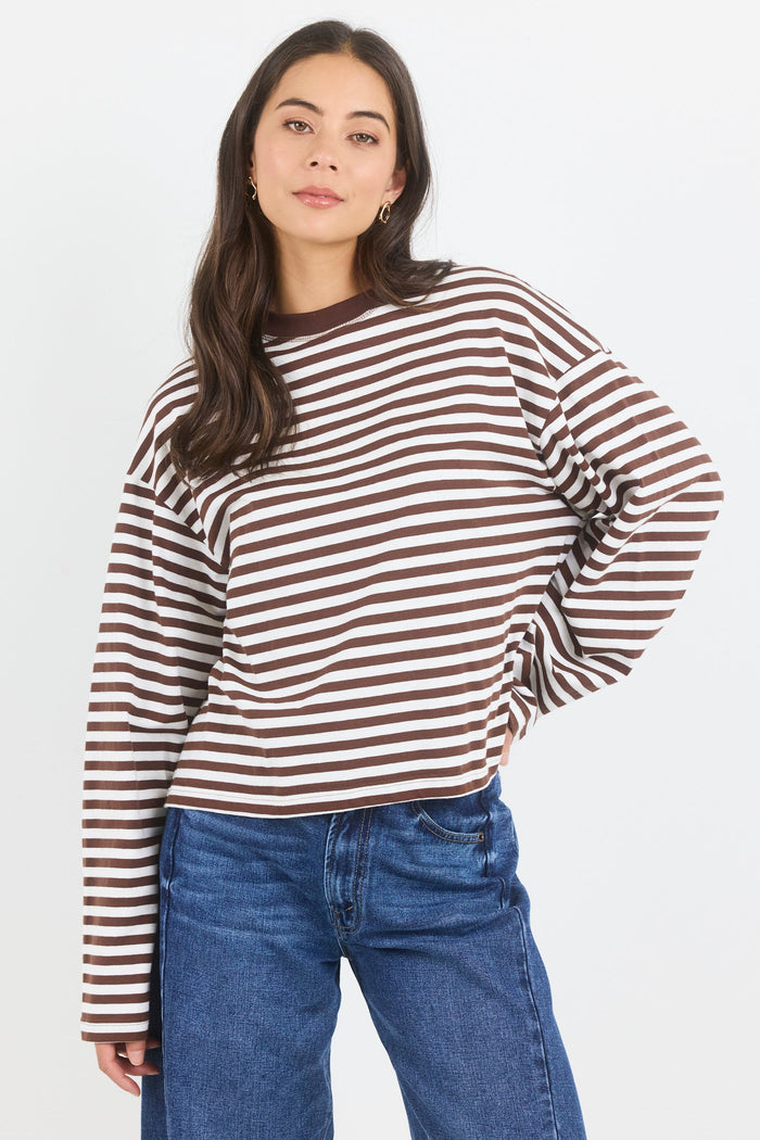 Woman wearing a striped long-sleeve shirt and blue jeans on a white background