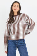 Woman wearing a striped long-sleeve shirt and blue jeans on a white background