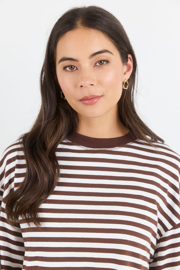Woman wearing a brown and white striped shirt against a plain background