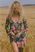 Model wearing floral Onyx mini dress front-on, lace-up tie detail and wide-cuff long sleeves, wheat field setting