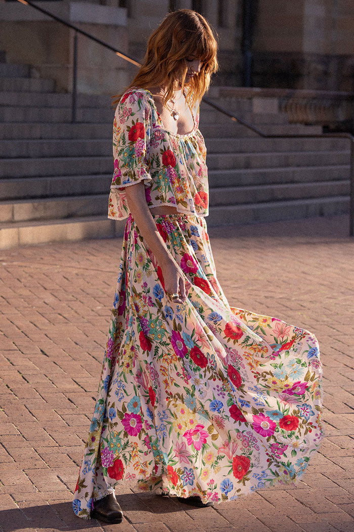 Side view of a model wearing the Valley of the Dolls floral TENCEL maxi skirt, skirt swirling to show hi-lo hem