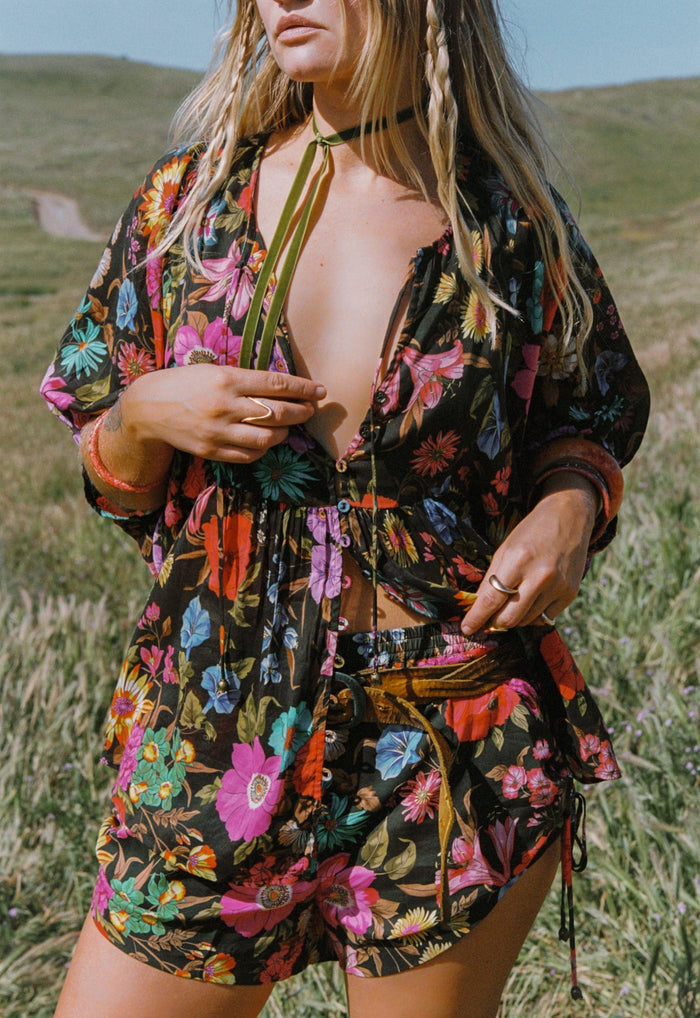 Model wearing Onyx floral ECOVERO viscose shorts, front view showing elastic waist and side ruching with ties