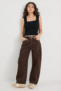 Woman wearing a black tank top and brown pants on a white background