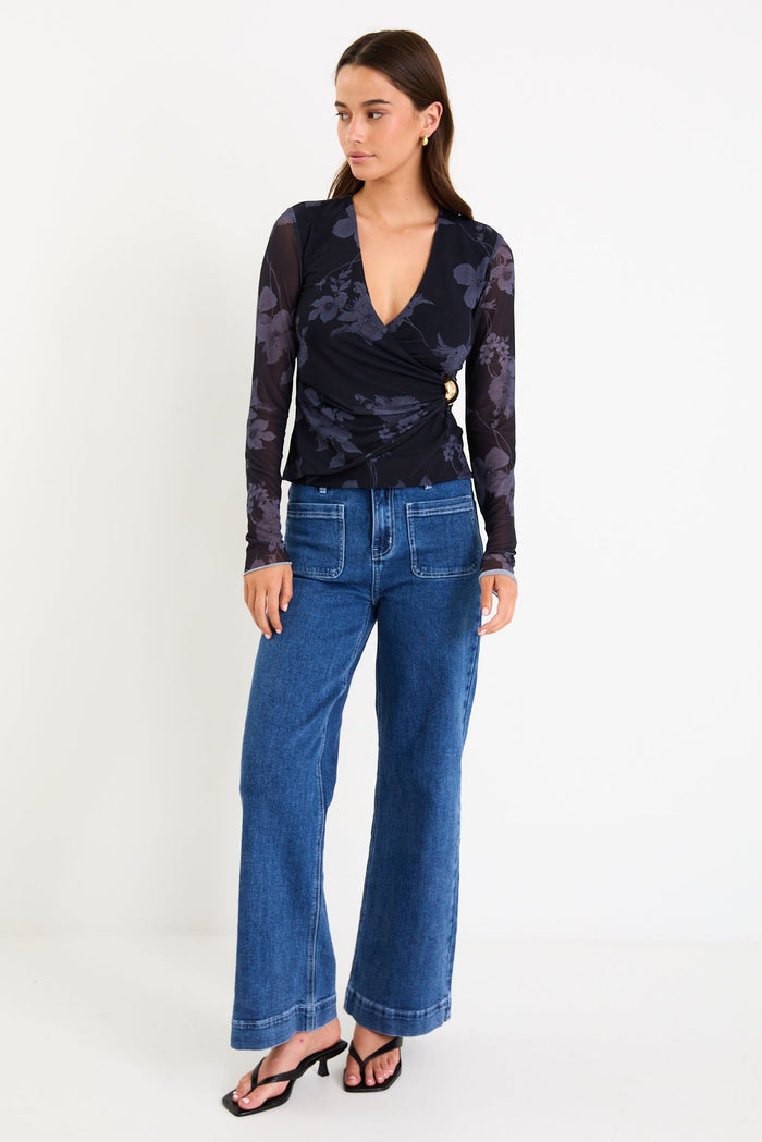 Model wearing a long-sleeve midnight floral mesh crossover top with gathered waist detail and gold hardware.