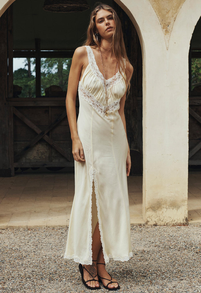 Model wearing buttermilk TENCEL slip dress, front view showing lace hem detail and front split