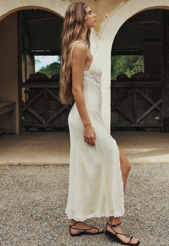 Side profile of a model in buttermilk TENCEL slip dress, lace waist detail and front split visible