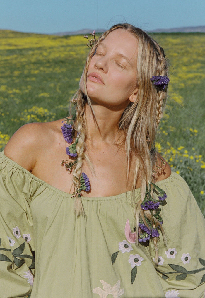 Close-up front view of off-shoulder organic cotton mini dress in lime, showing floral appliqué detail on puff sleeve