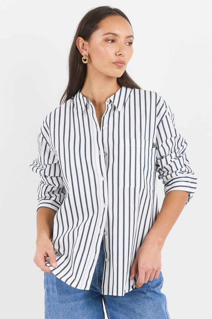 Woman wearing a black and white striped shirt and blue jeans on a white background