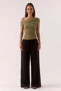 Woman wears a green ruched top and black pants