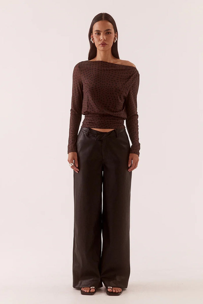 Woman wearing a brown off-shoulder top and wide-leg pants on a white background